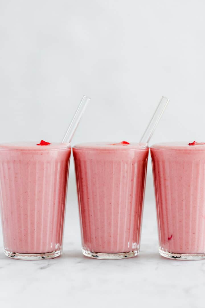 3 glasses filled with vegan strawberry smoothie