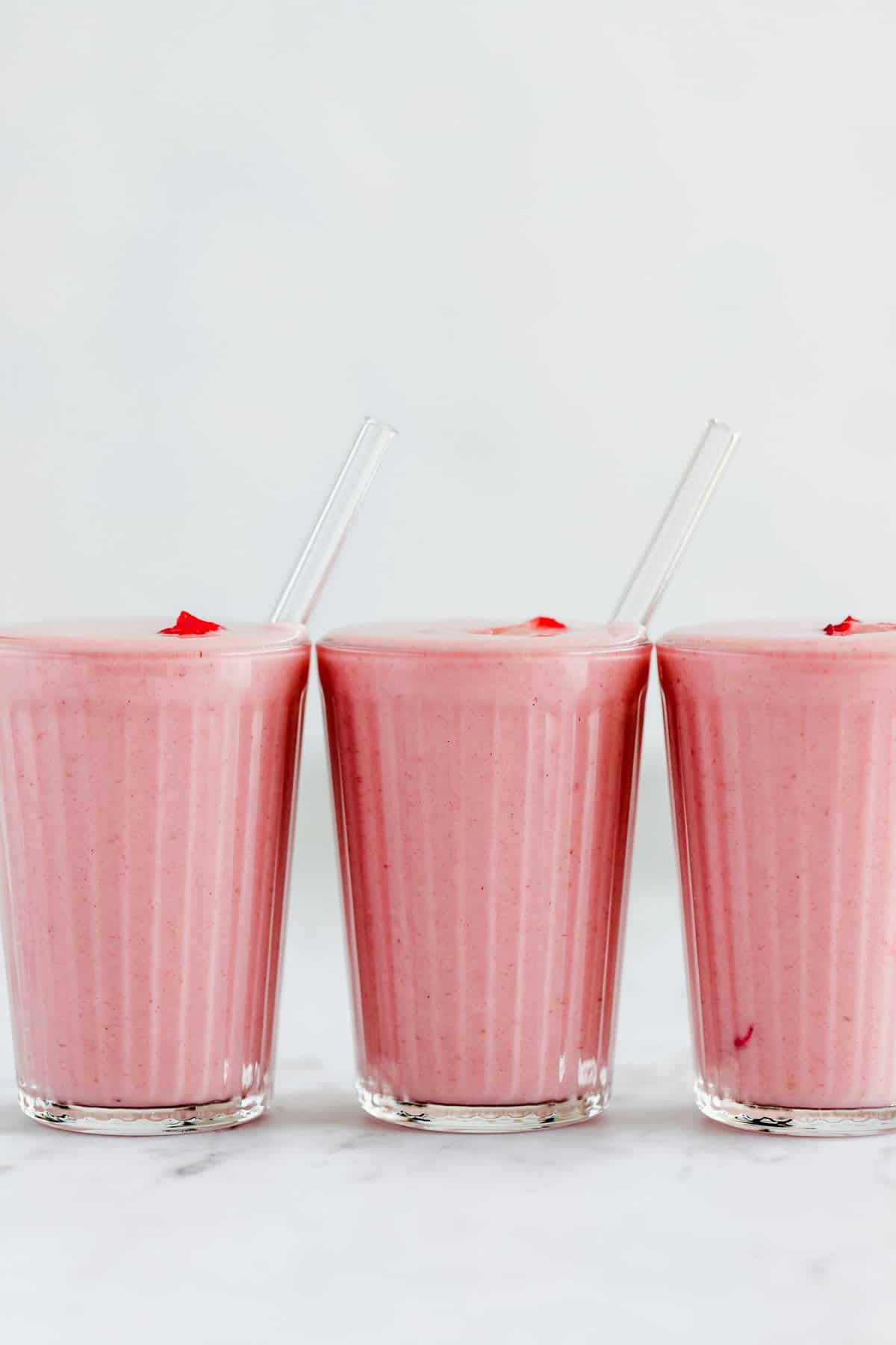 3 glasses filled with vegan strawberry smoothie