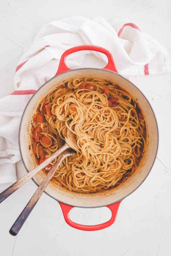 cooked vegan one pot pasta with tomatoes and basil in a red pot