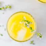 selbstgemachte mango limonade in einem glas mit eiswürfeln und thymian