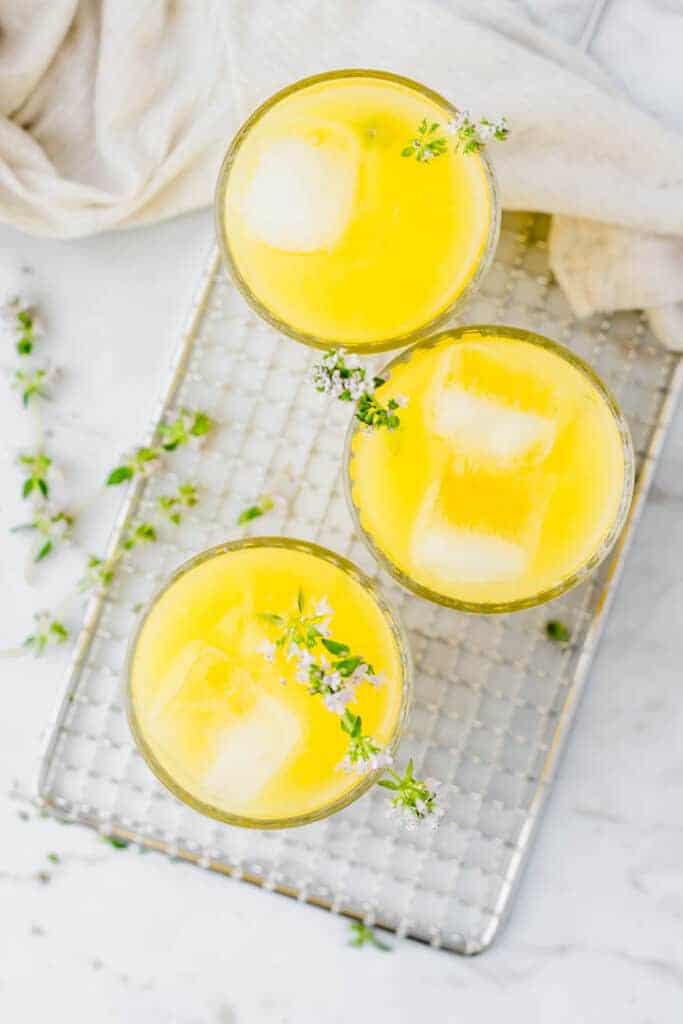 3 glasses filled with freshly made lemonade on a silver potato grater