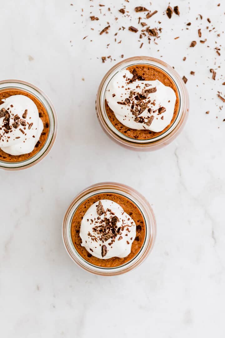 vegan chocolate mousse topped with dairy free whipped cream and grated chocolate