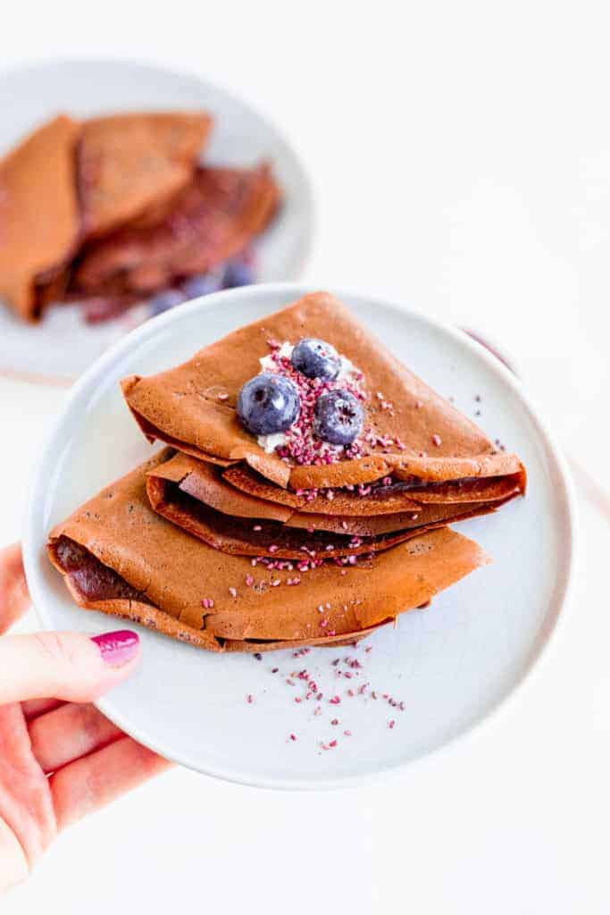 chocolate crepes topped with blueberries on a blue plate