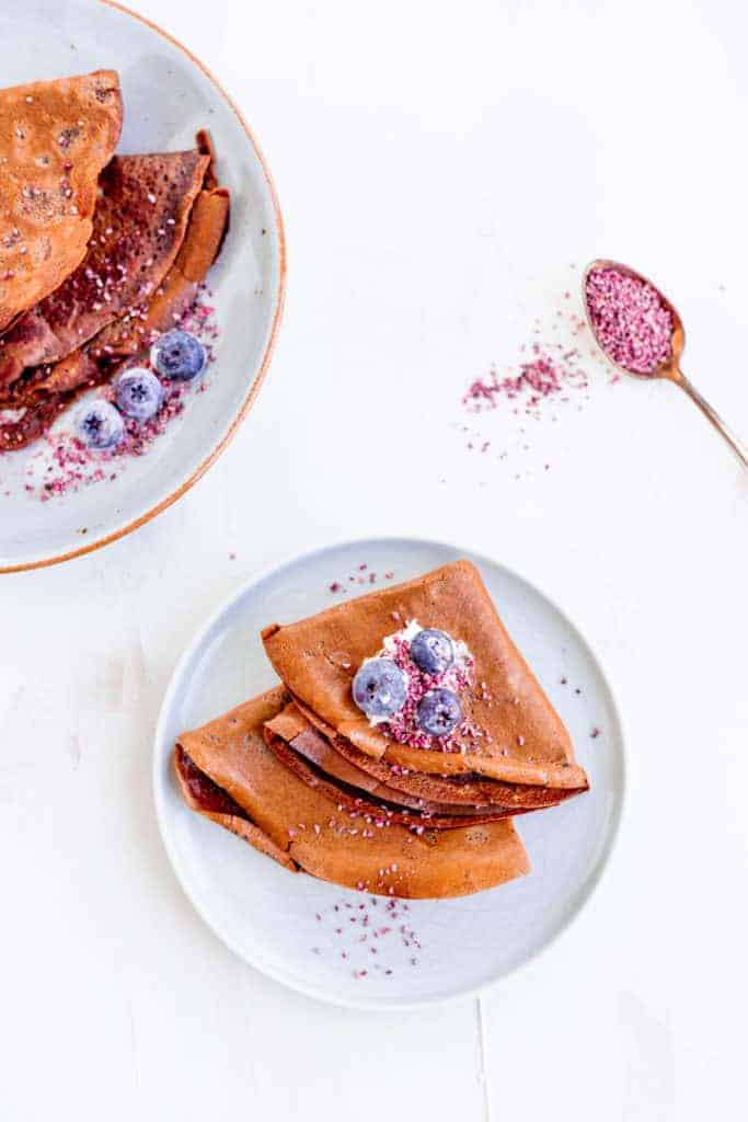 chocolate crepe recipe stabled on a blue plate topped with strawberry seeds