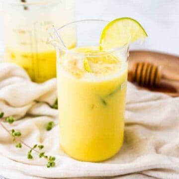 vegan mango lassi served in a large glass with lime slices