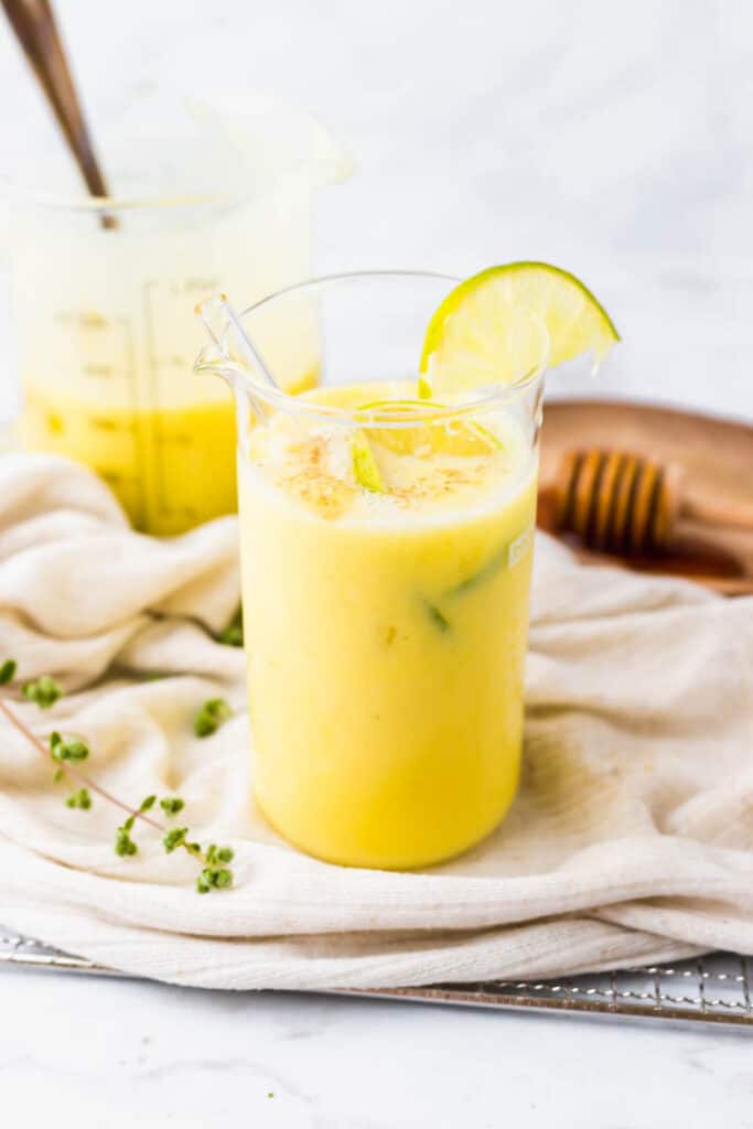 vegan mango lassi served in a large glass with lime slices