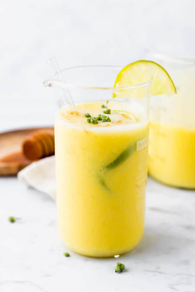 indian vegan mango lassi served in a glass with lime slices