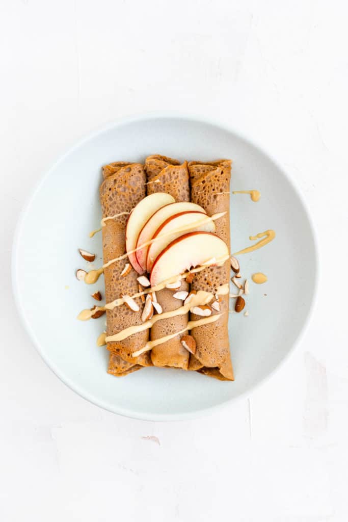 gluten-free buckwheat crepes topped with almonds, almond butter, and nectarine wedges