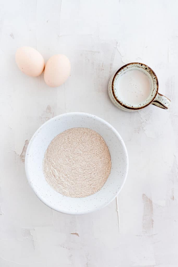 eggs, buckwheat flour, and milk on a white table