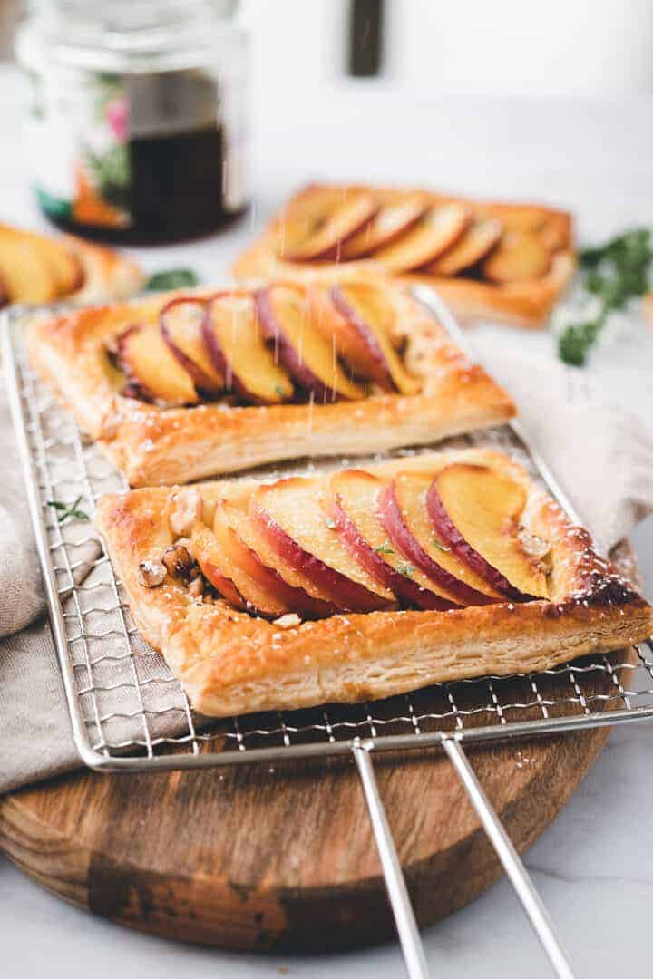 caster sugar sprinkled peach tarts on a wooden board