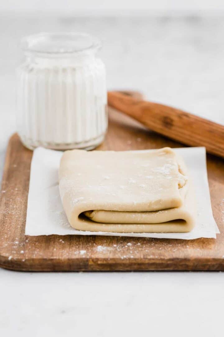 3 layered vegan pastry on a board next to flour and a rolling pin