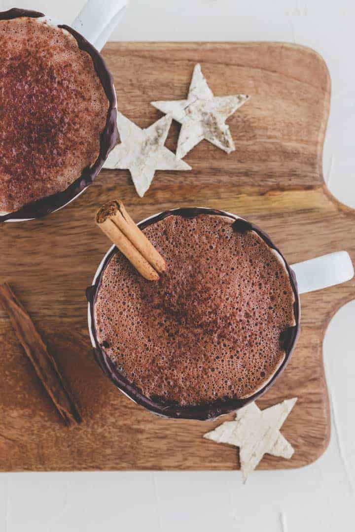 best vegan hot chocolate recipe on a wooden board with little starts and a cinnamon stick