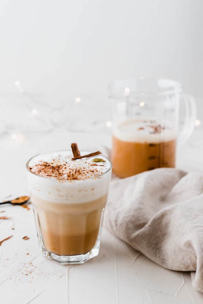 chai tee auf weissem tisch mit lichterkette im hintergrund