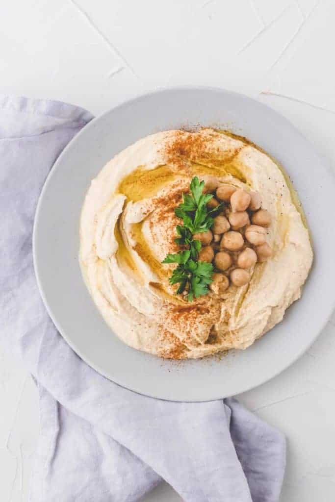 Hummus Rezept mit Olivenöl, Kichererbsen, und Petersilie dekoriert