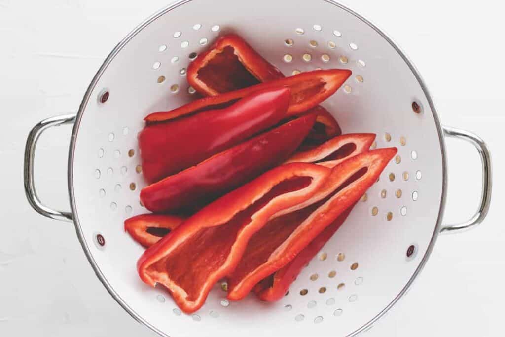 washed and halfed red peppers in a white bowl