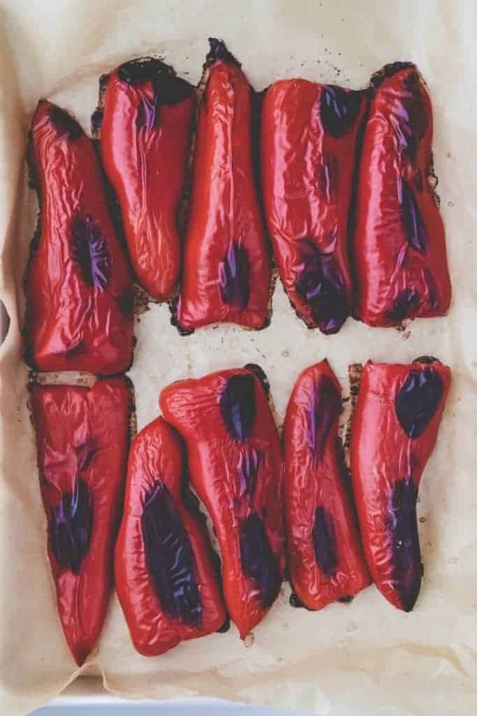 roasted red peppers on a parchment paper after they are coming out of the oven