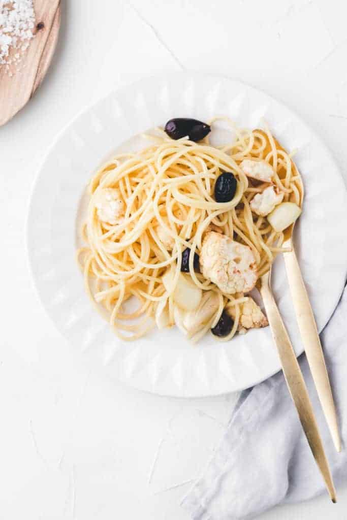 roasted cauliflower pasta served in a white plate with golden cutlery