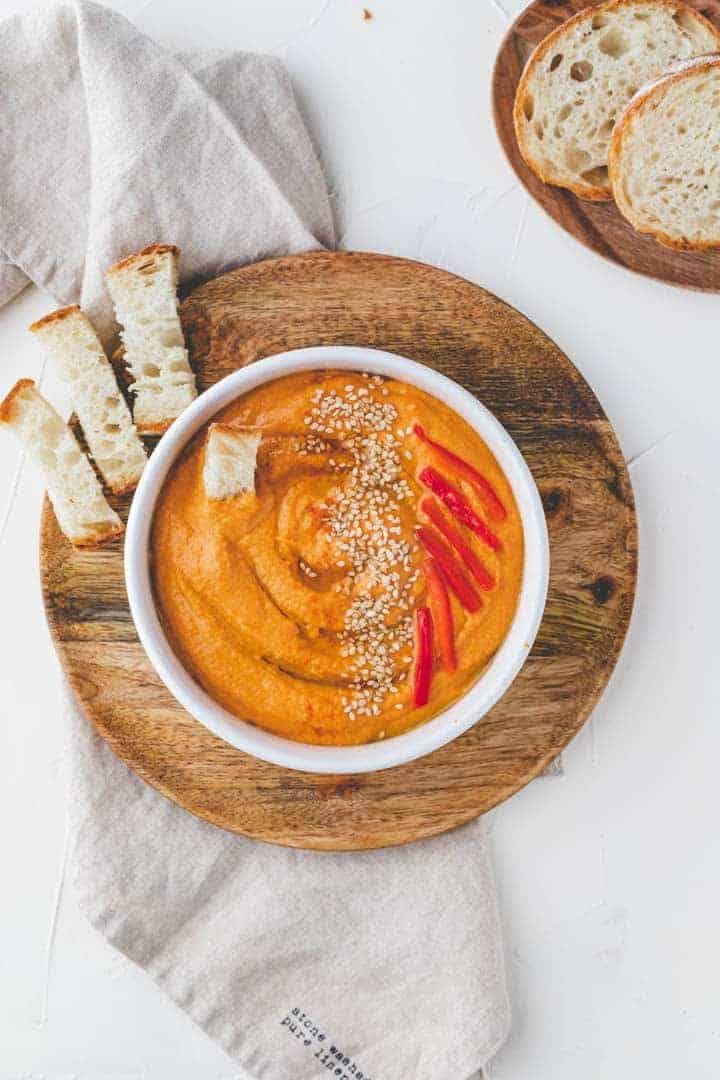 Paprika Hummus Rezept mit Sesam, Olivenöl, und Paprika dekoriert