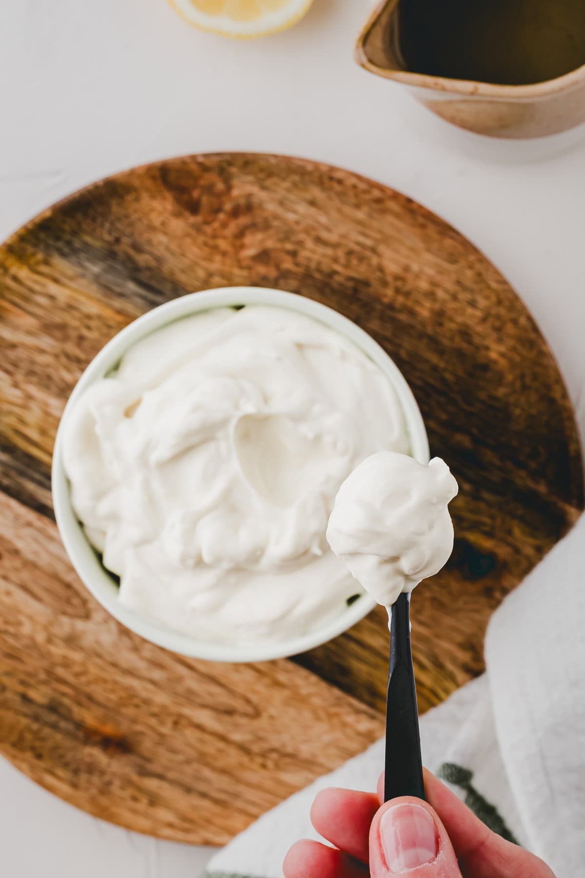 eine hand hält einen löffel mit veganer mayo