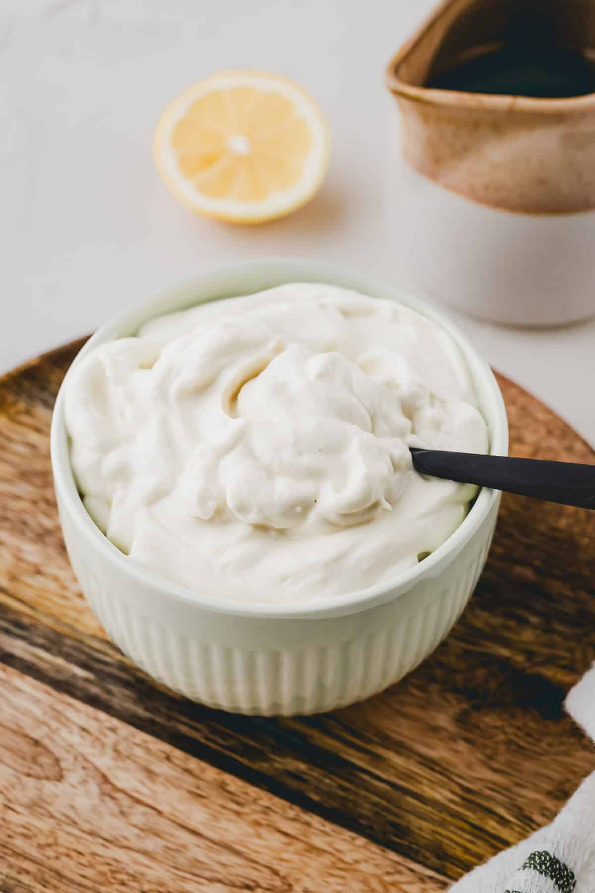 selbstgemachte vegane mayo in einer grünen schüssel mit einem schwarzen löffel