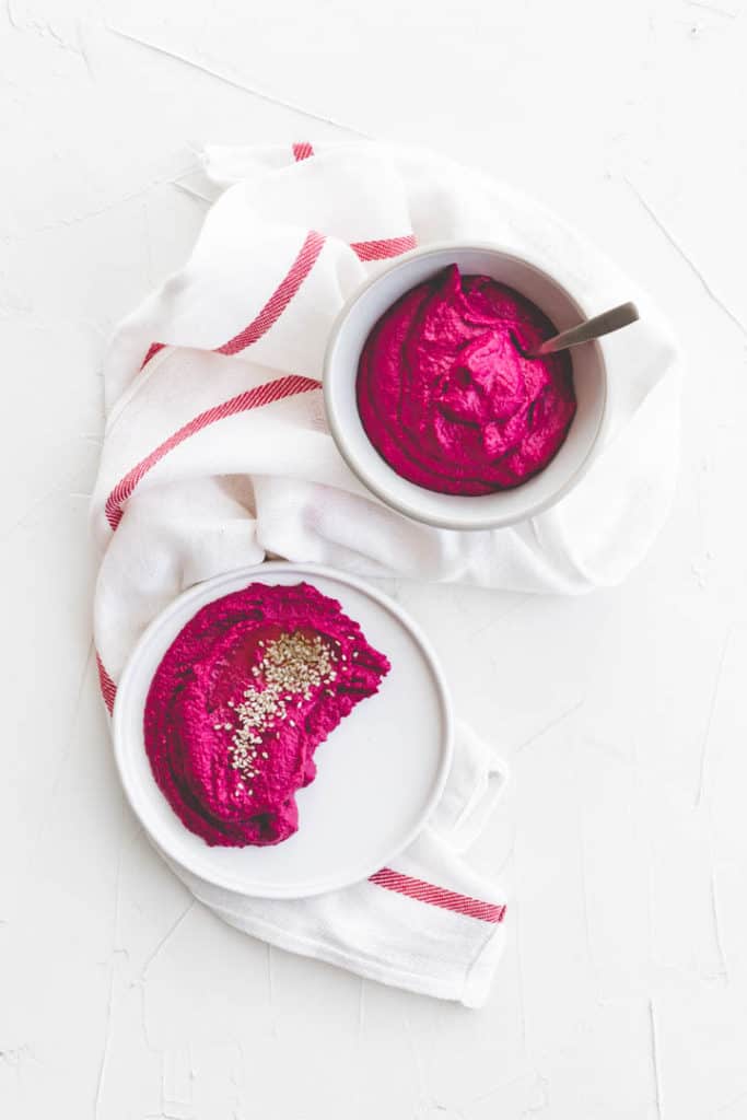 beetroot hummus in two white cups on a white towel