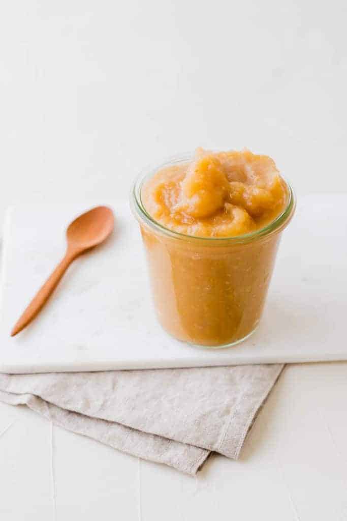 homemade unsweetened applesauce in a glass jar on a white background