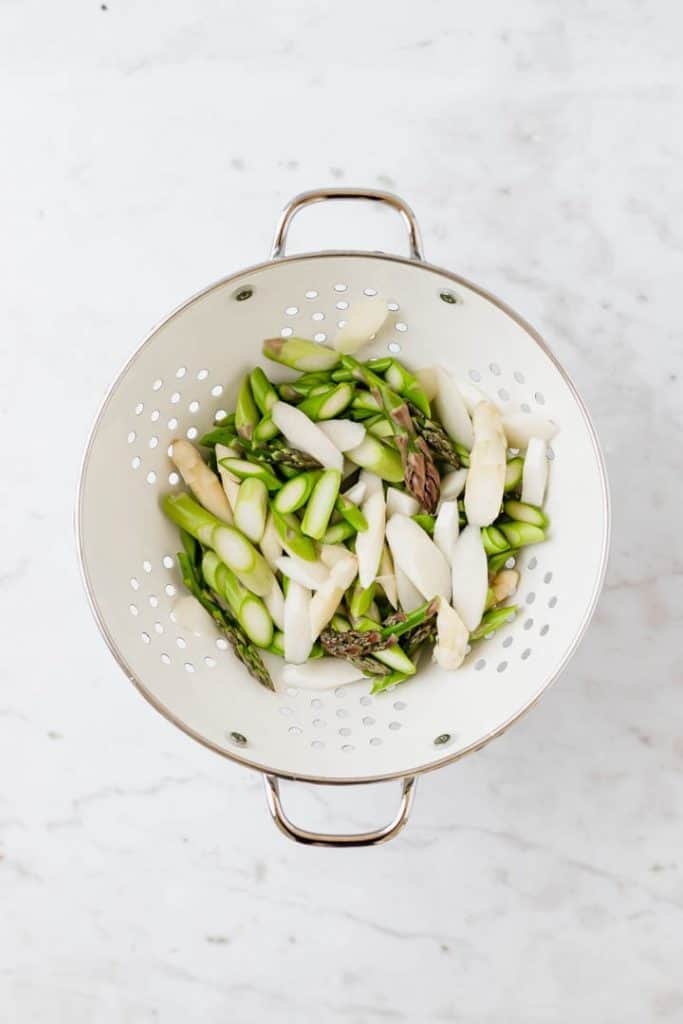 chopped white and green asparagus in a colander