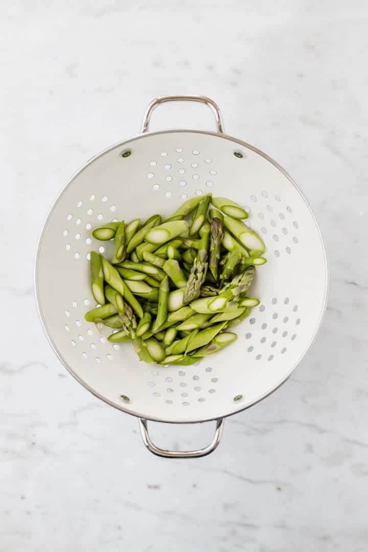 geschnittener grüner spargel in einem weissen küchensieb