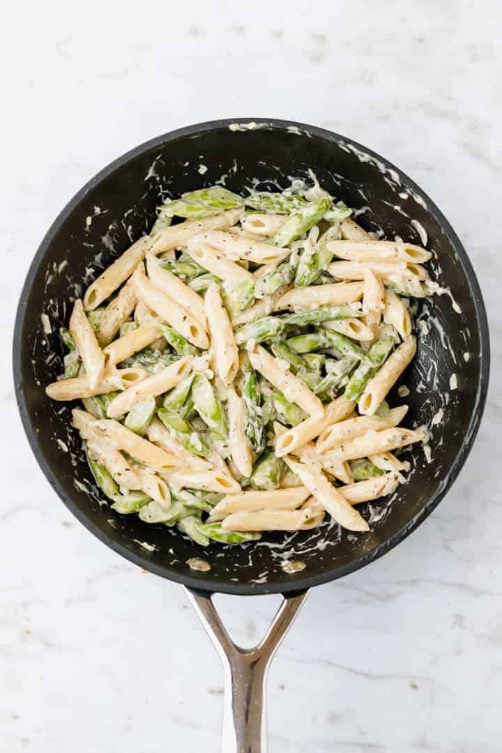 pasta, green asparagus, and vegan alfredo sauce in a skillet
