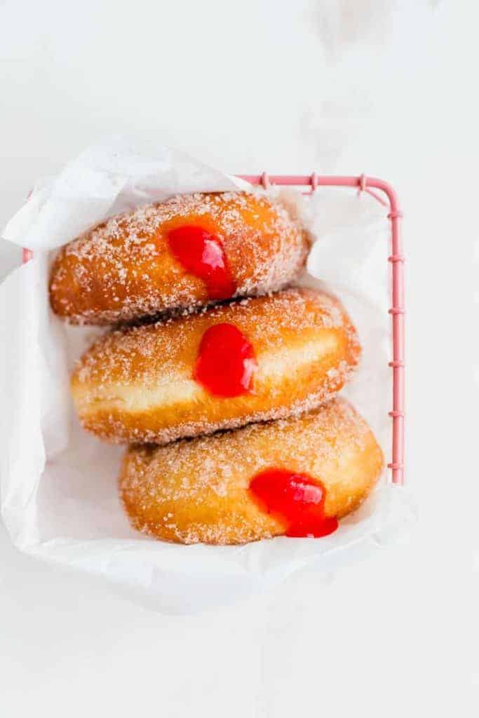 3 krapfen gefüllt mit erdbeer rhabarber marmelade in einem pinken körbchen