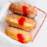 three jelly filled donuts in a pink basket