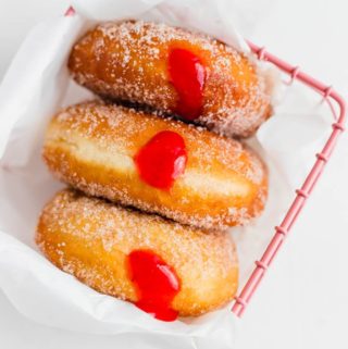 three jelly filled donuts in a pink basket