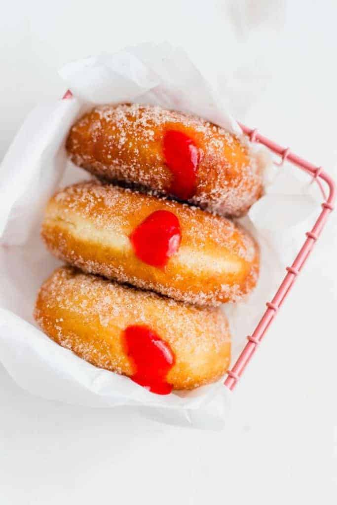 three jelly filled donuts in a pink basket
