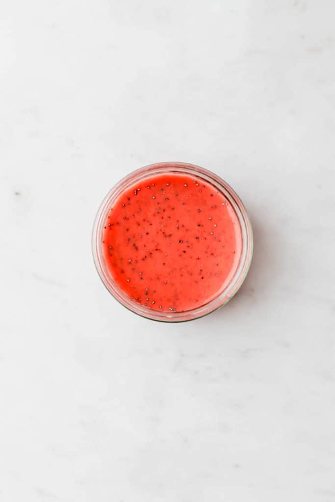 strawberry poppyseed dressing in a glass jar next to a wooden spoon