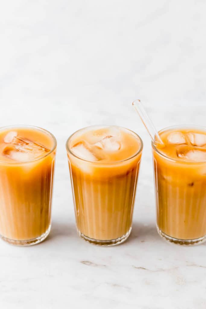 3 glasses of thai iced tea filled with iced cubes