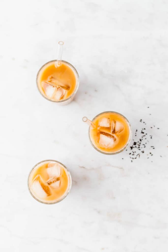 3 glasses of vegan thai iced tea on a marble dish