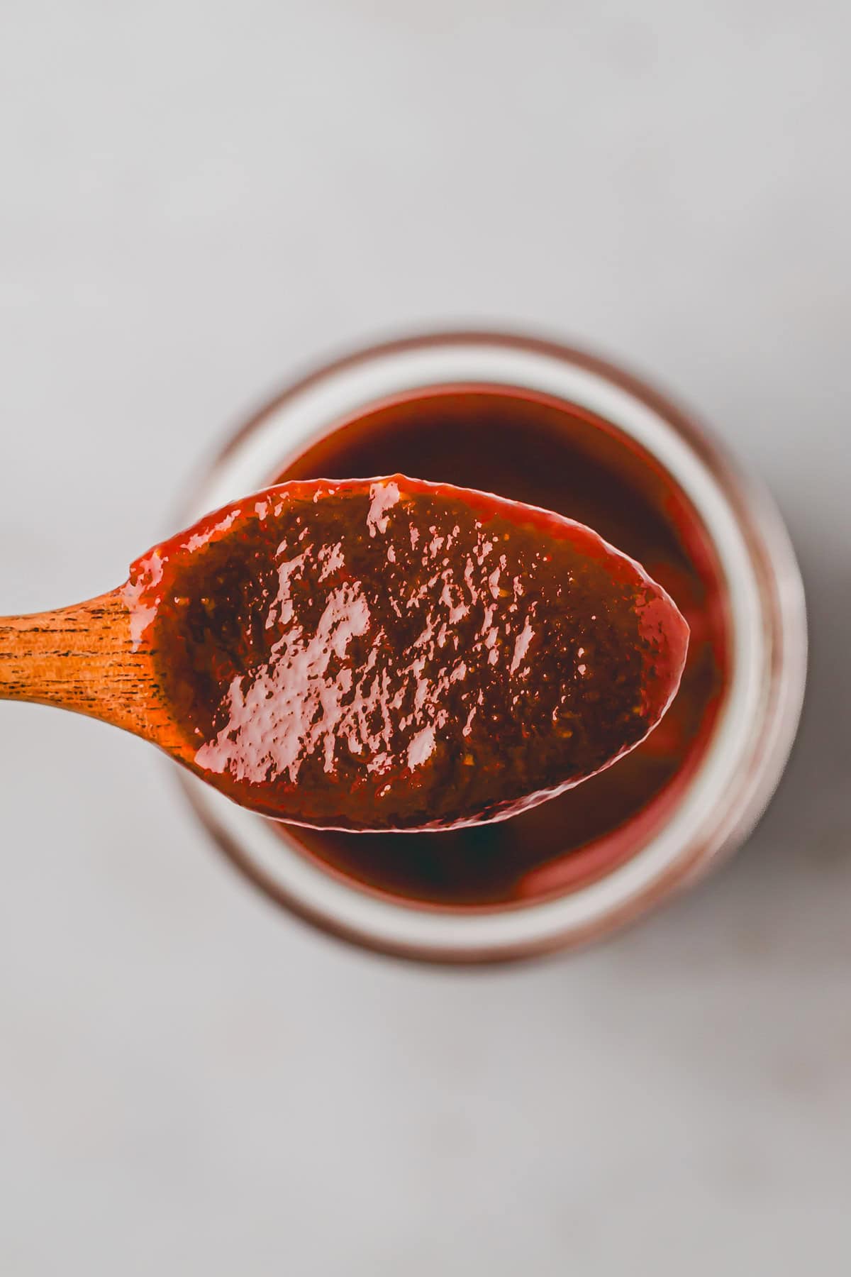 bbq sauce auf einem holzlöffel über einem glas