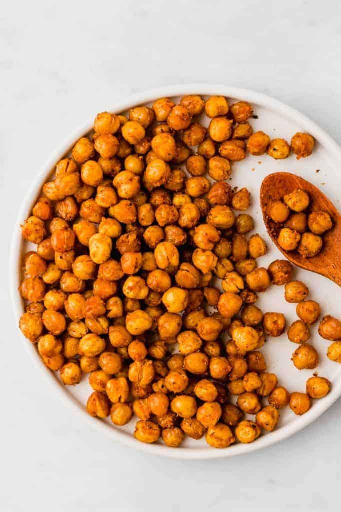 oven roasted chickpeas on a white plate with a wooden spoon