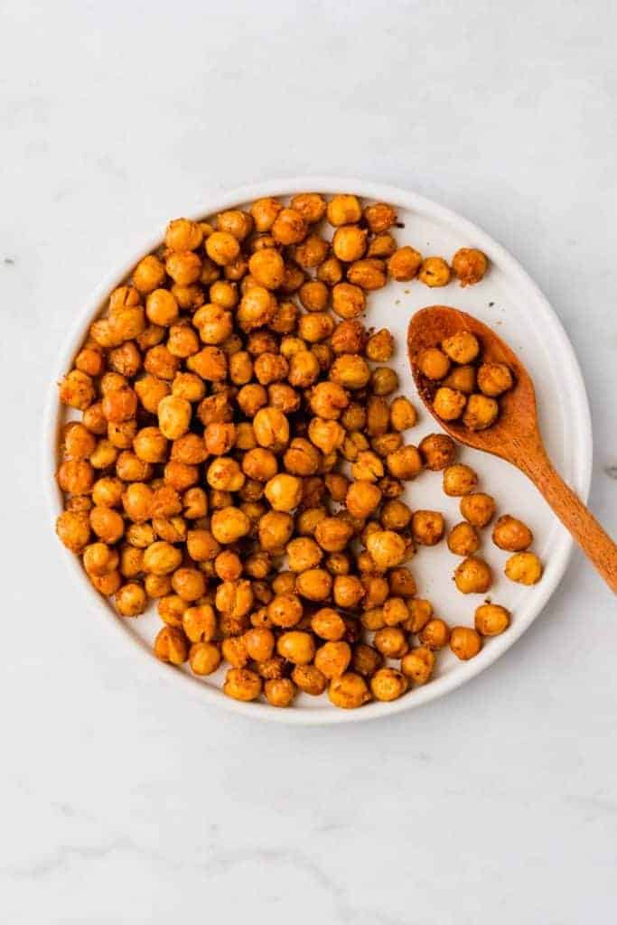 oven roasted chickpeas on a white plate with a wooden spoon