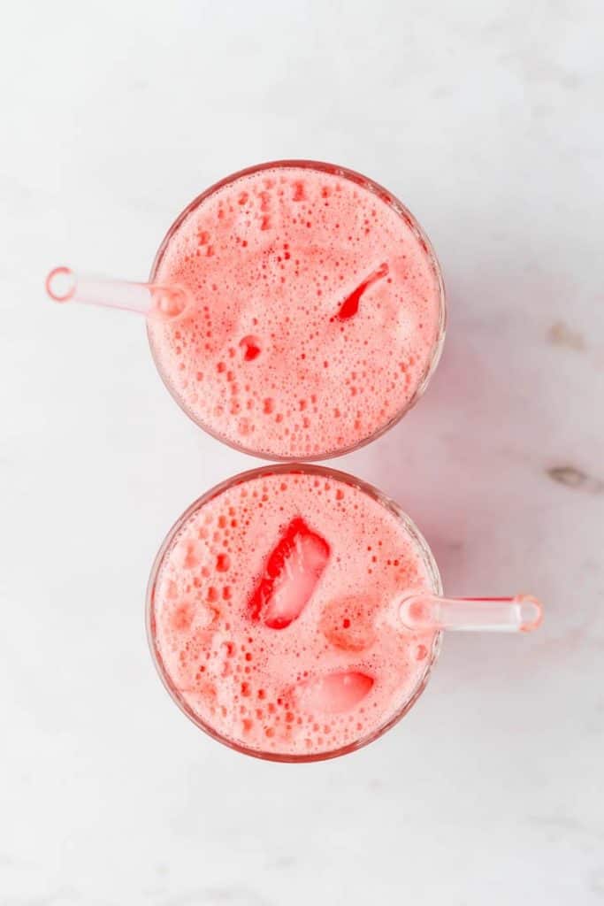 two glasses filled with watermelon water and ice cubes