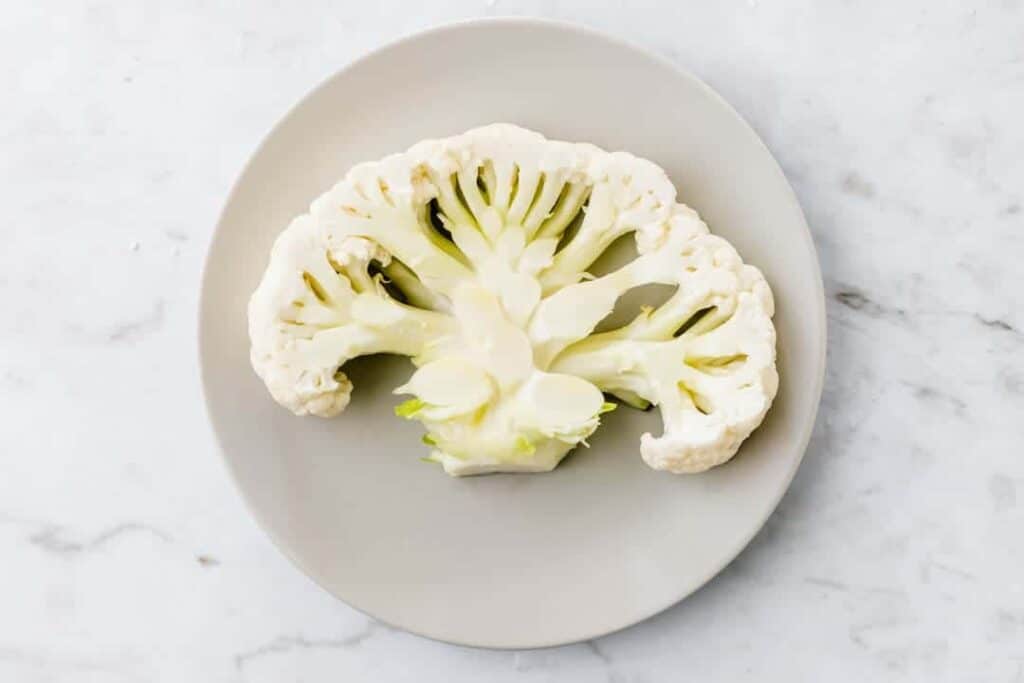 raw cauliflower steak on a grey plate