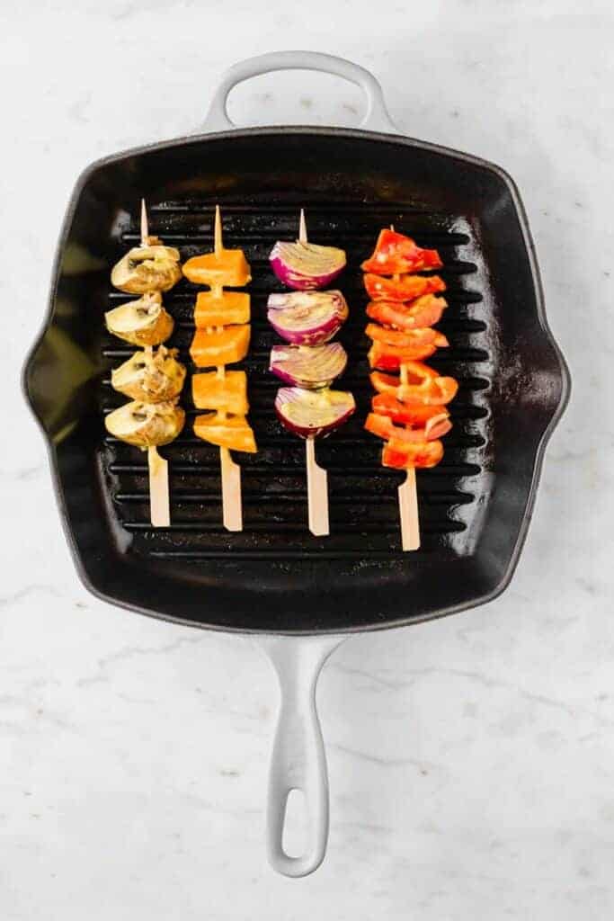 vegetable skewers grilling in a grill pan
