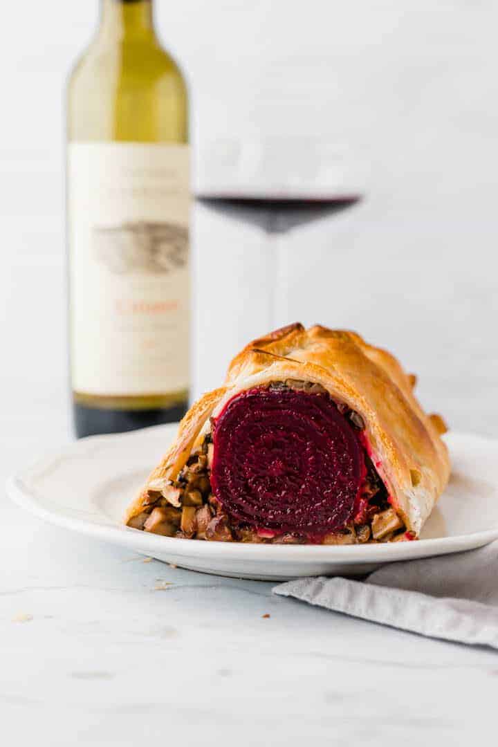 veganes beet wellington serviert mit einer flasche rotwein