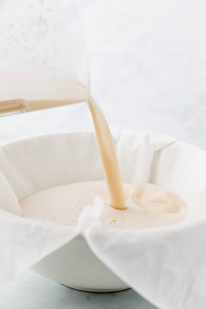 non dairy milk poured into a cheesecloth over a bowl