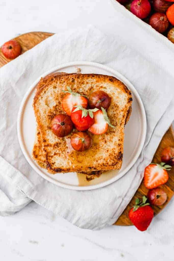 vegan french toast serviert auf einem weissen teller mit beeren und ahornsirup