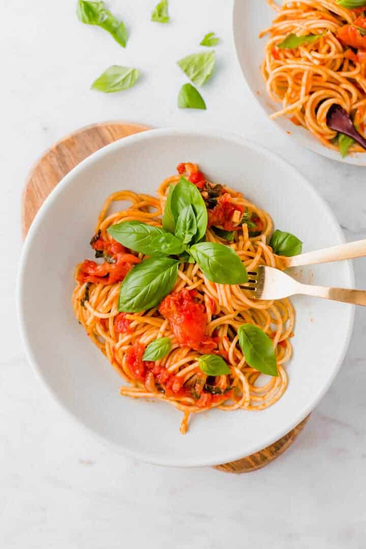 pasta pomodoro serviert in einem blauen teller mit goldenem besteck