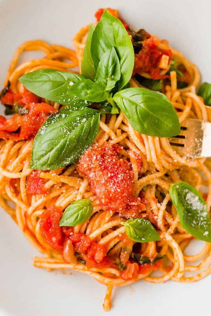 pasta al pomodoro serviert mit frischem basilikum und veganem parmesan