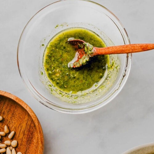 Basilikum Pesto ohne Parmesan in einem glasschällchen mit einem holzlöffel