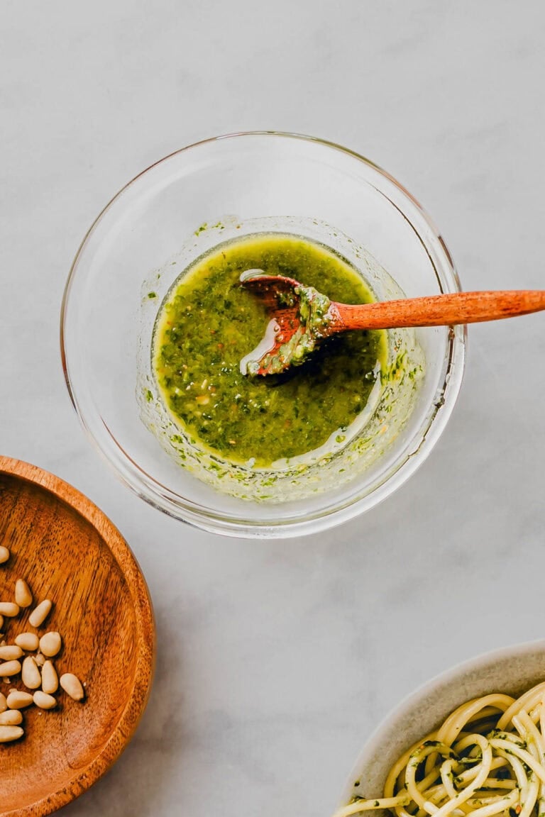 Basilikum Pesto ohne Parmesan in einem glasschällchen mit einem holzlöffel