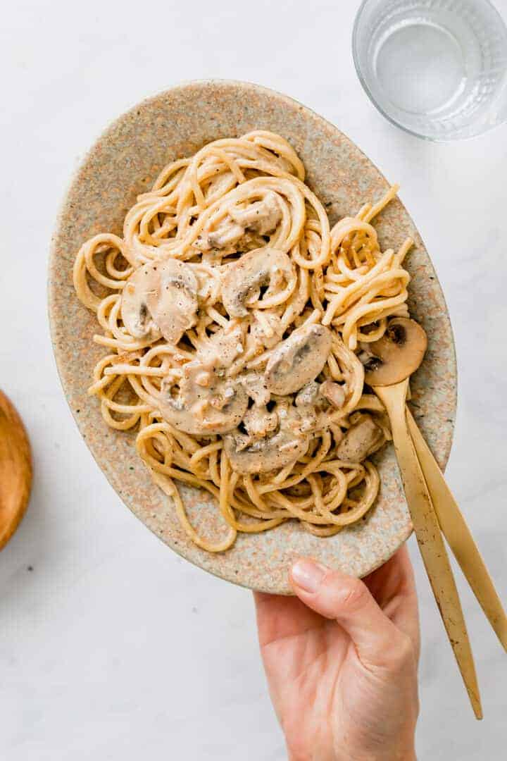 vegan pasta carbonara served on a plate with golden cutlery